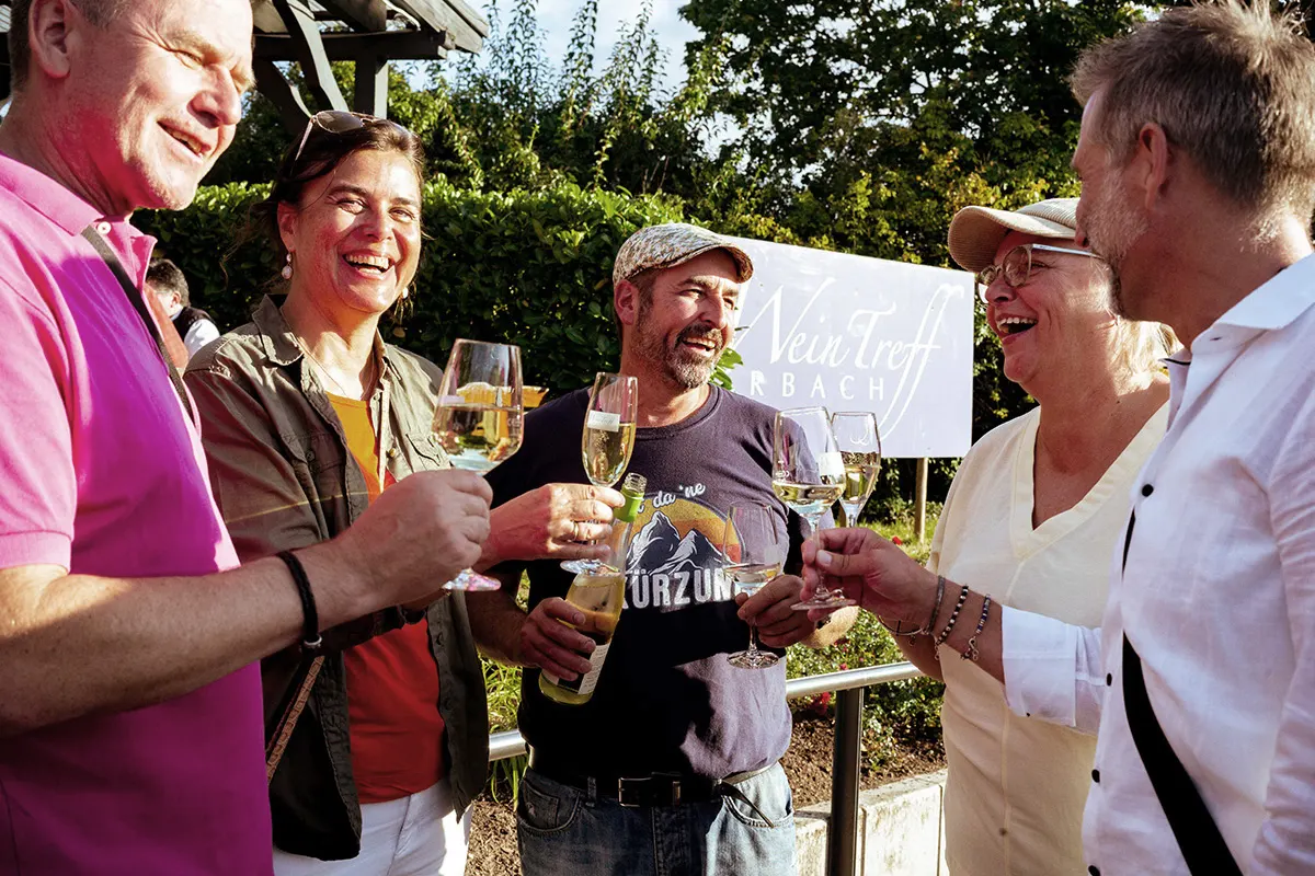Gesellige Szene mit einigen Freunden am Weintreff. Die fünf stoßen mit einem Glas Wein an und lachen!